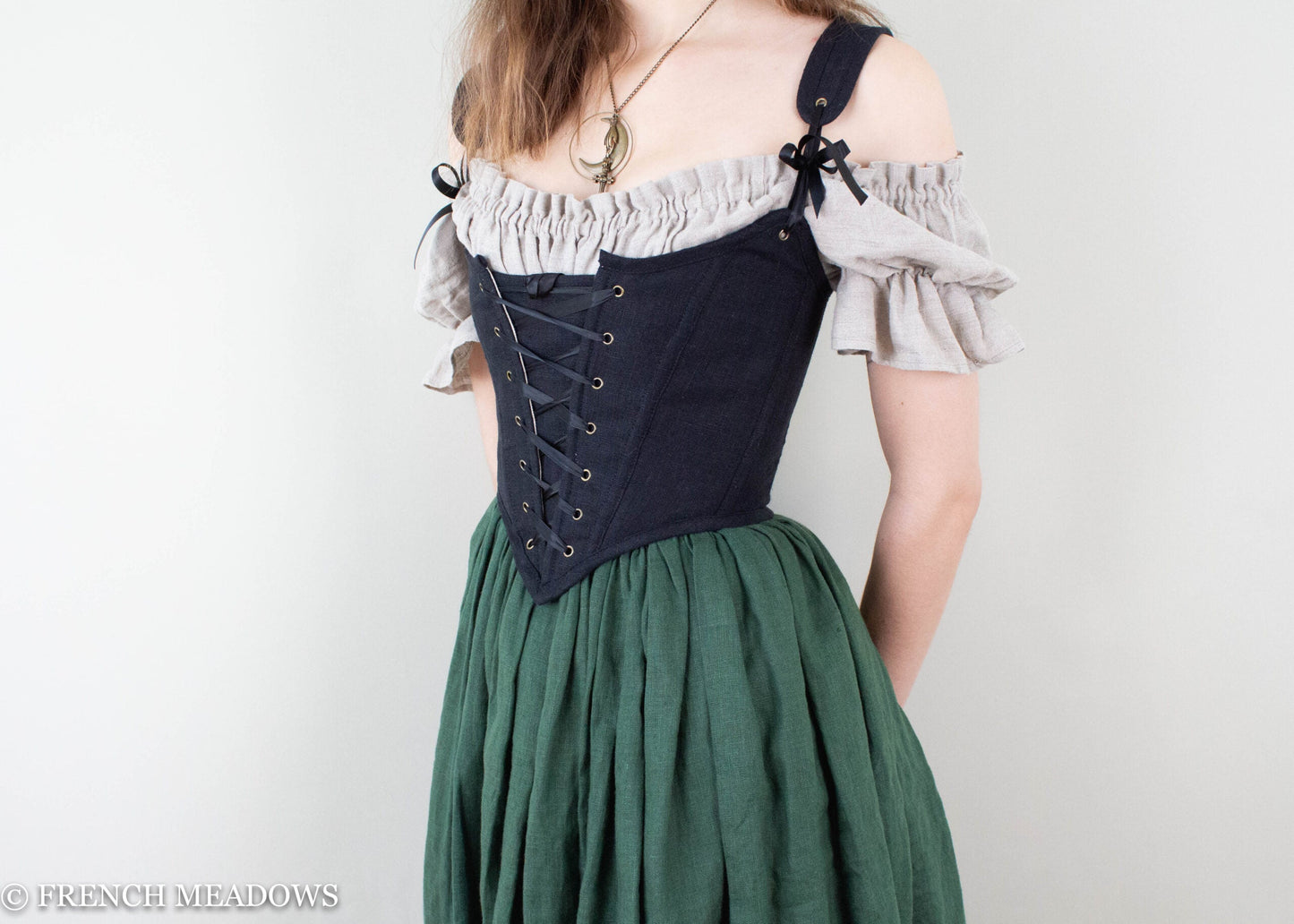 modeling wearing a black corset top paired with a green linen skirt