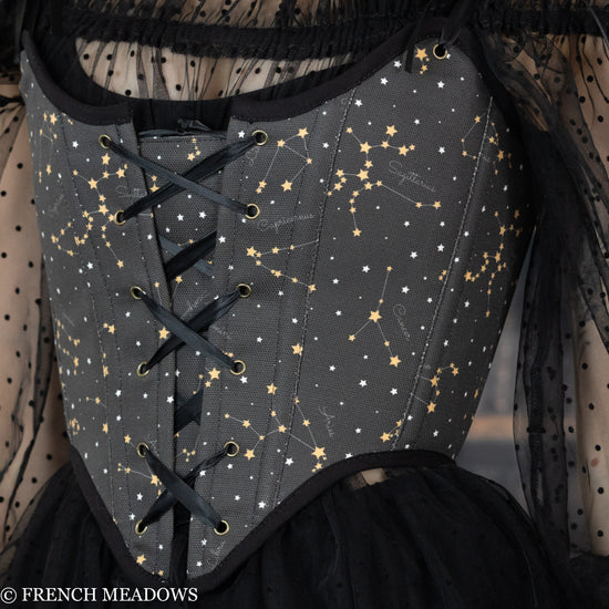 close up view of a black corset with gold constellations and the names of zodiac signs