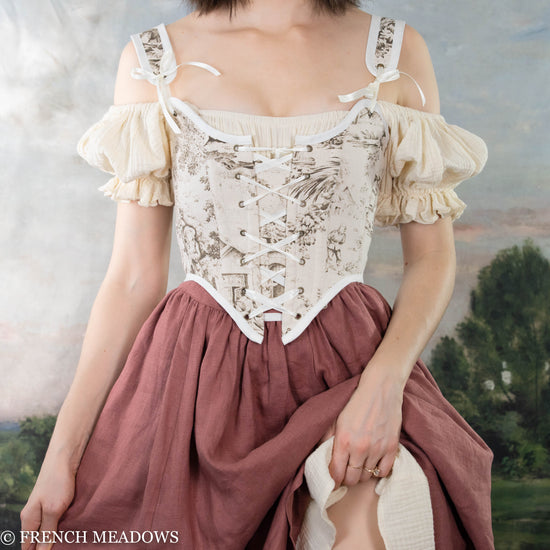 model wearing brown renaissance bodice with a cream colored chemise worn off the shoulders