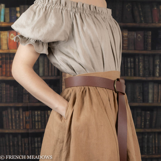 model putting her hand into the pockets of a brown linen skirt