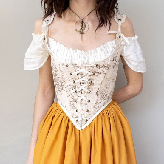 model wearing a brown renaissance corset with a golden yellow skirt
