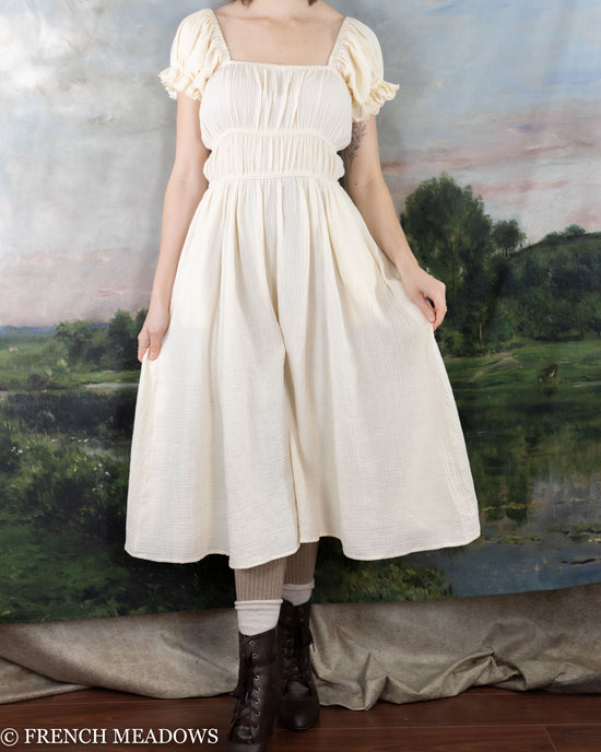 Load image into Gallery viewer, model wearing a romantic ivory cotton dress that has an A-line skirt shape
