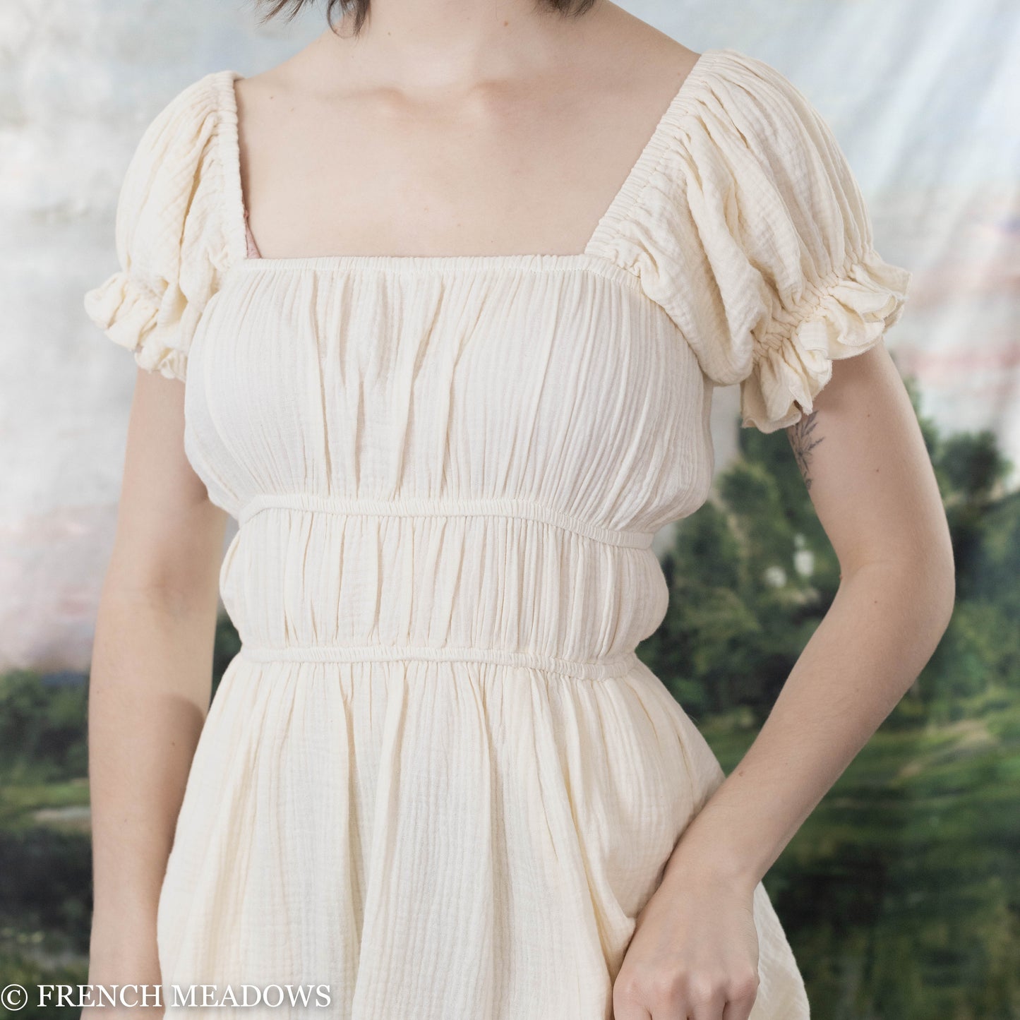 a white cotton dress with elastic rouching under the bust and at the waist in a classic milkmaid style