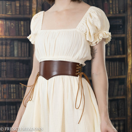 model wearing brown leather waist harness over cream colored renaissance dress