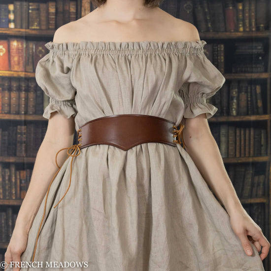 front view of model wearing pointy leather waist belt in brown variation