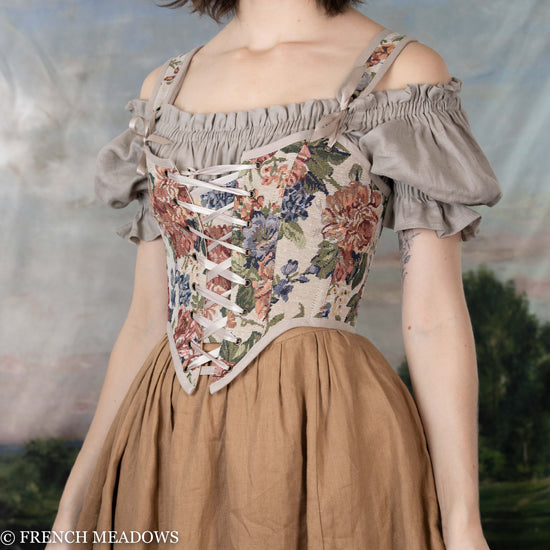 side view of model wearing a floral corset paired with a light brown linen dress and a brown linen skirt