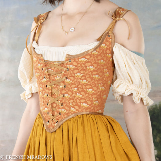 close up view of a model wearing a light orange floral renaissance bodice
