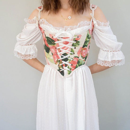 model wearing a pink corset over a white lacey cotton nightgown