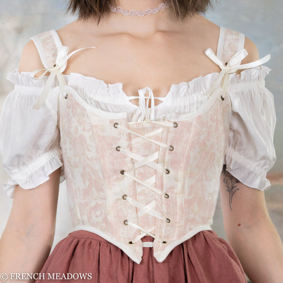 close up view of a pink renaissance corset with an 18th century inspired pattern