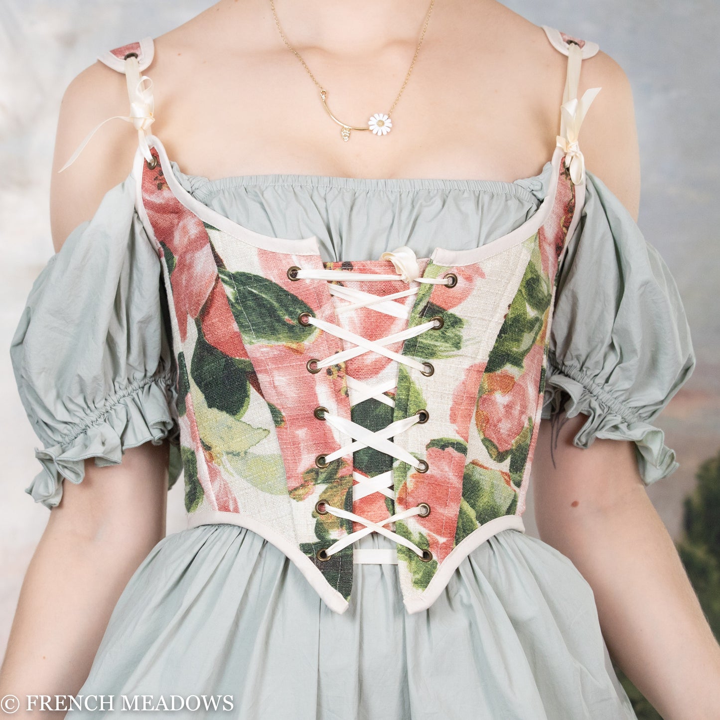 close up details of pink floral renaissance corset top shows large peony flower details and green leaves