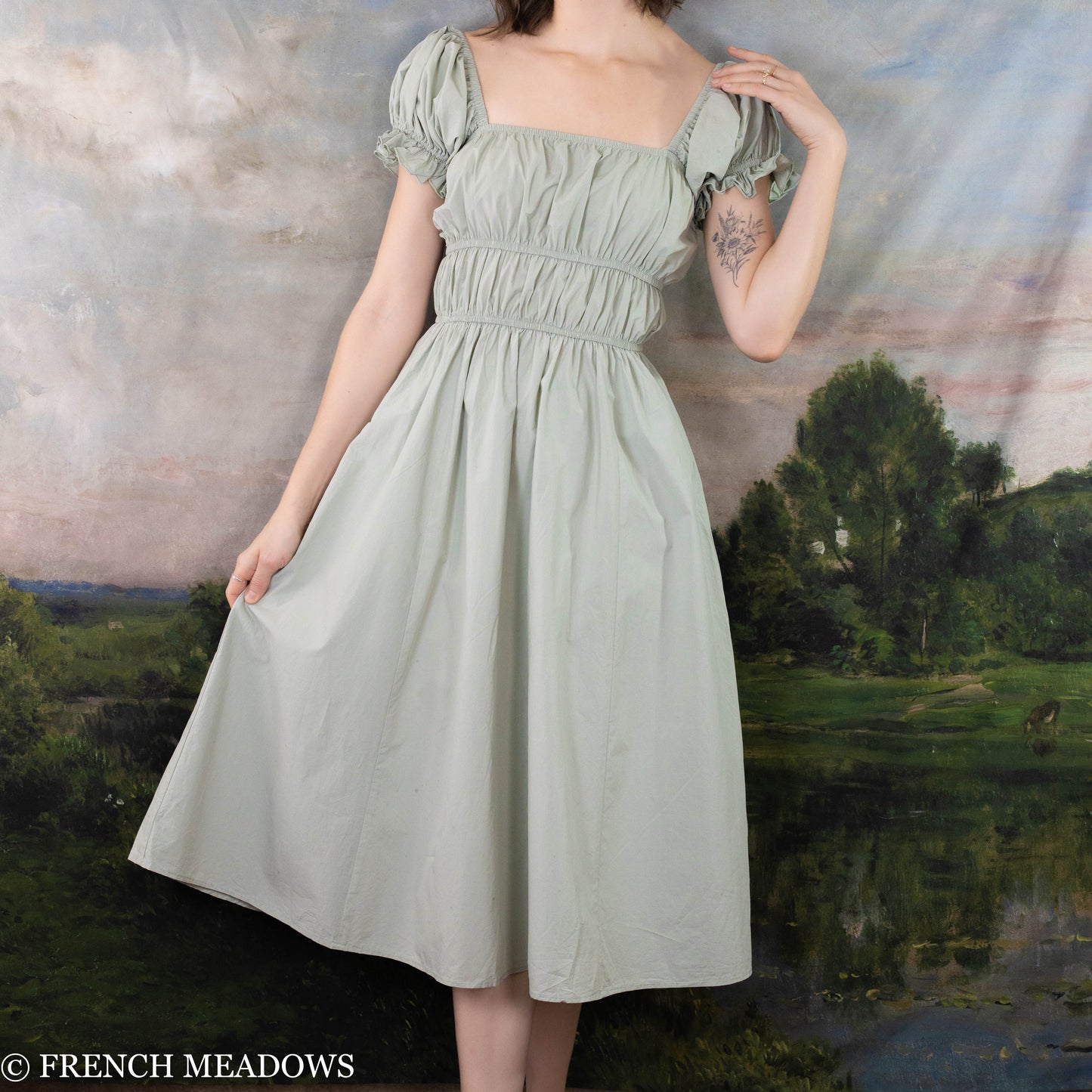 modeling holding out the a-line skirt of her pastel green romantic dress