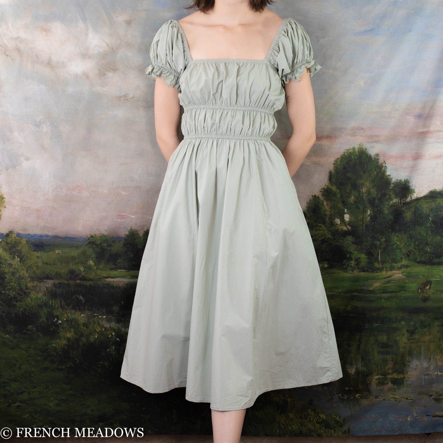 modeling wearing a green cottage core dress with waist rouching