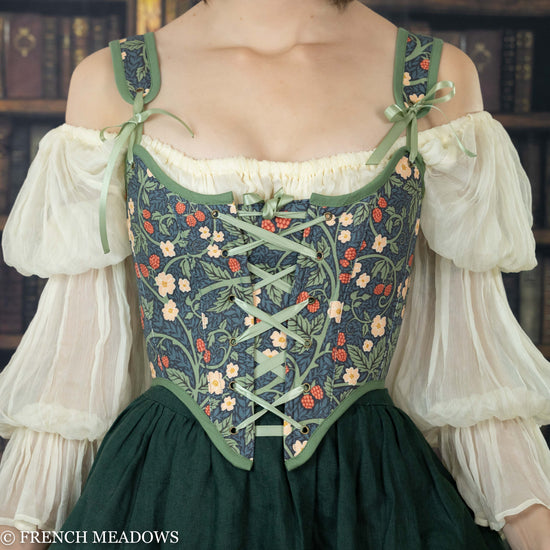 model wearing a corset top with a floral green fabric featuring vines, leaves, and raspberries