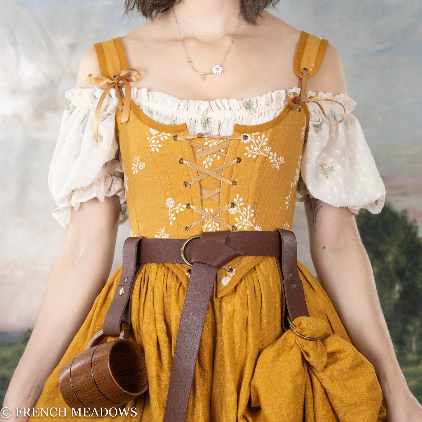 model wearing a renaissance faire costume with a yellow corset, skirt, and leather belt accessories for the renaissance faire